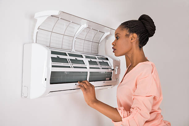 Young African Woman Checking Air Conditioner not blowing cold air